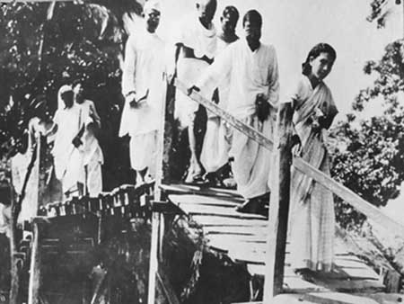 Gandhiji while crossing an inprovised bridge along with Dr. Sushila Nayar, Charu Chowdhury, Pyareelal Nayar.jpg